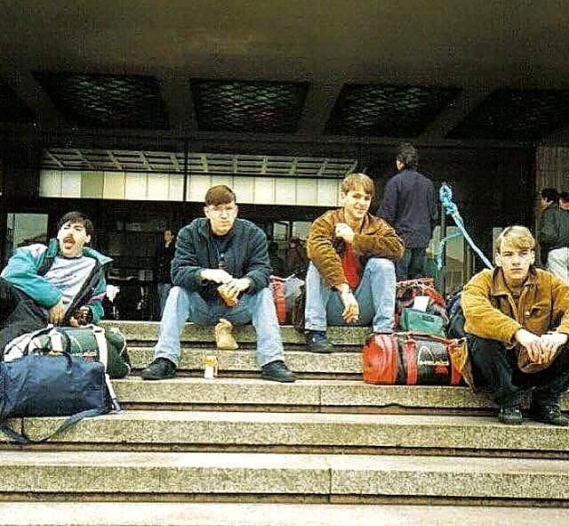 Group of lads in the late 80s sitting on steps with their sports holdalls ready for a trip away